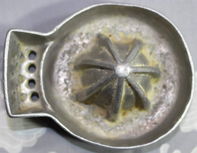 Top view of an aluminium saucer shape juicer with a side mounted drain