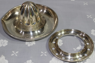 The 2 parts of a Suckling Ltd silver plate juicer without handle