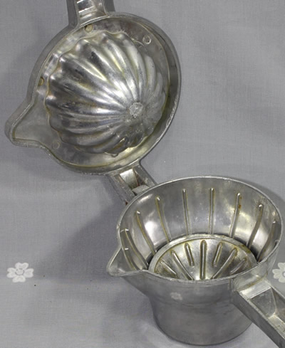 Showing the insert in a hinged aluminium hand squeezer juicer