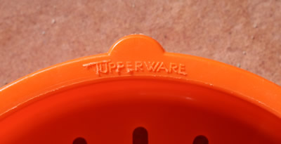 The embossed logo on an orange Tupperware juicer insert