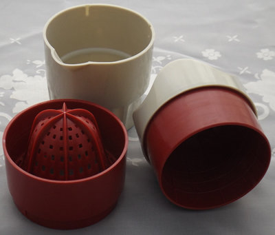 The 3 pieces of a red and grey plastic juicer