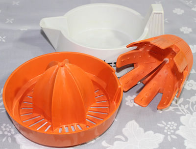 The 3 parts of a Zyliss white and orange plastic juicer 