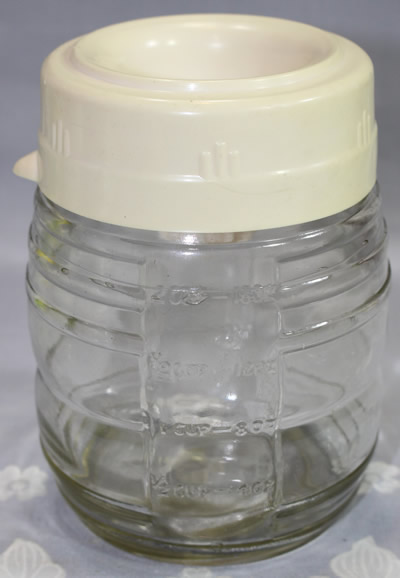 Closed cream coloured plastic juicer on glass jar