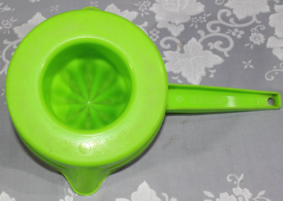 The base of a lime green and red Decor plastic pot shape juicer
