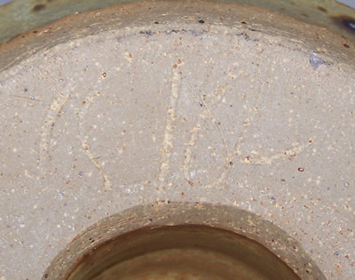 The potter's signature on a speckled light tan pottery juicer