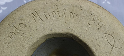 The potter's mark on a greys and brown pottery bowl juicer with leather loop