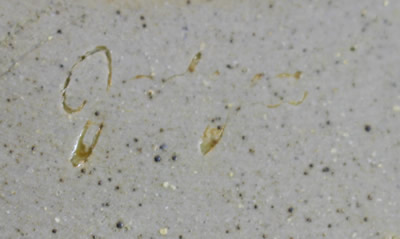 The potter's signature on a tan with stripe loop handle pottery juicer 