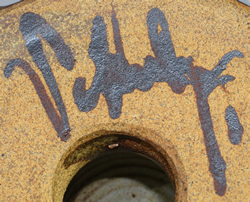 Potter's mark on tan loop handle with bow pottery juicer