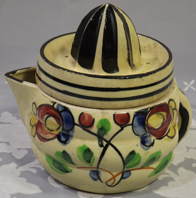 Red flowers and green leaves on a beige ceramic juicer