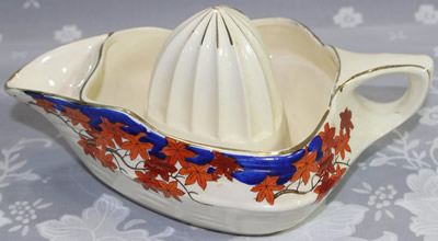 Red, orange, brown leaves with blue and gold trim on white Japanese ceramic juicer