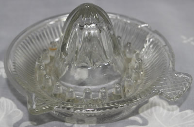 A small clear glass juicer with lattice pattern on the tab handle