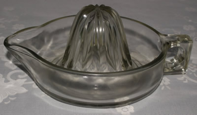 A large unembossed clear glass loop handle juicer