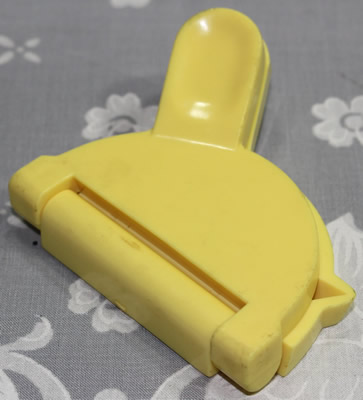 A small yellow plastic lemon wedge squeezer