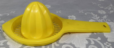 Yellow plastic hand held juicer