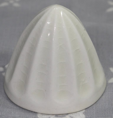 A small white ceramic jelly mould that looks like a juicer